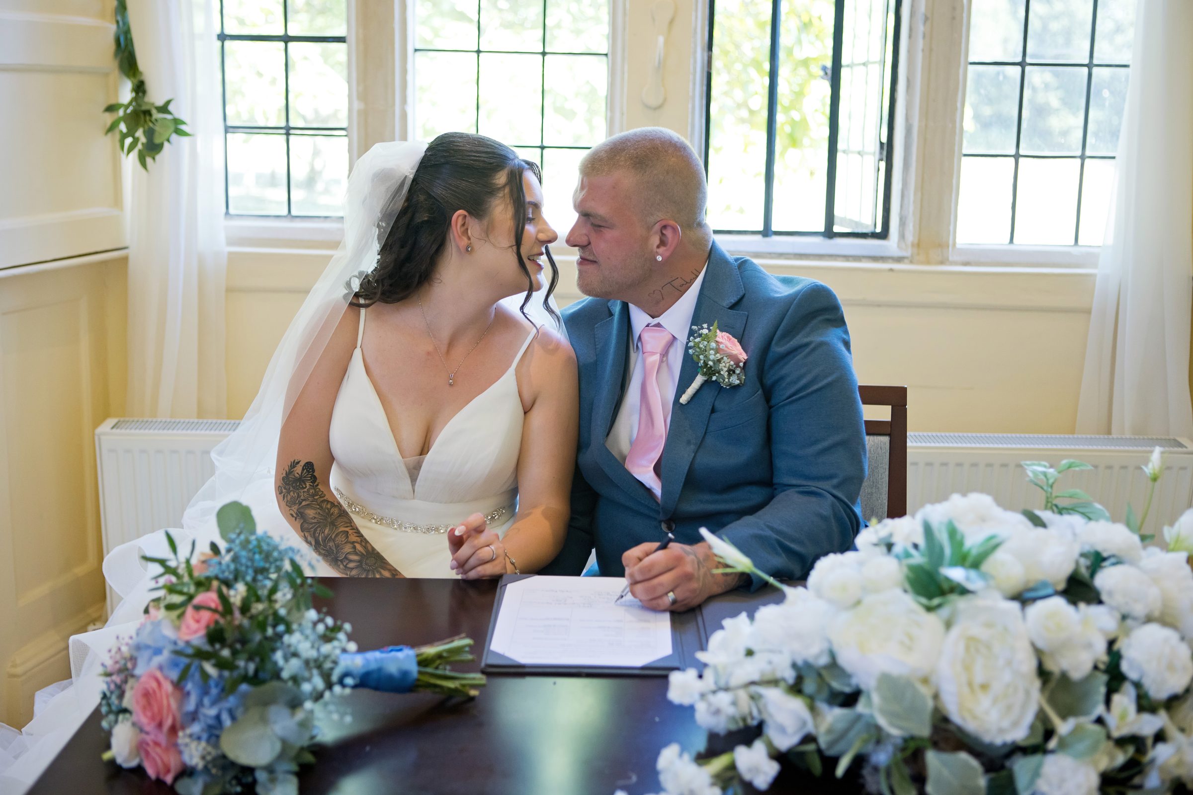 Melli and Ryan signing the register, forehead to forehead